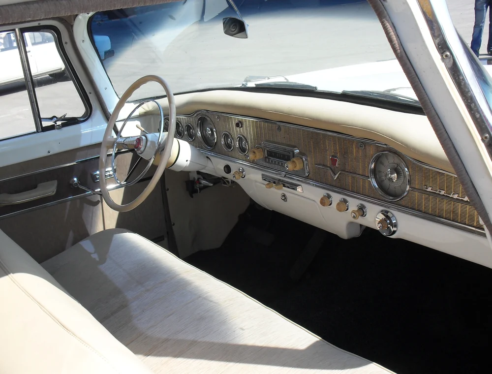 Clean classic car interior with light upholstery and dashboard detail