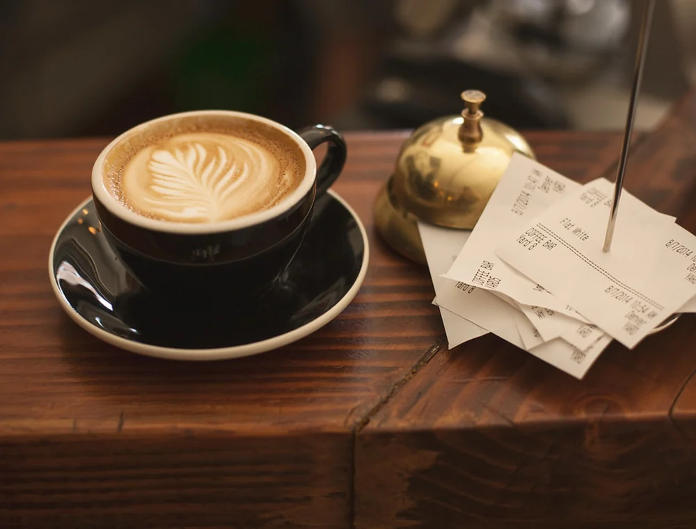 Cappuccino on a cafe counter beside small order tickets