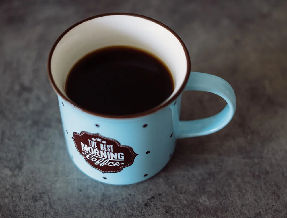 Black coffee in a blue mug on a dark table